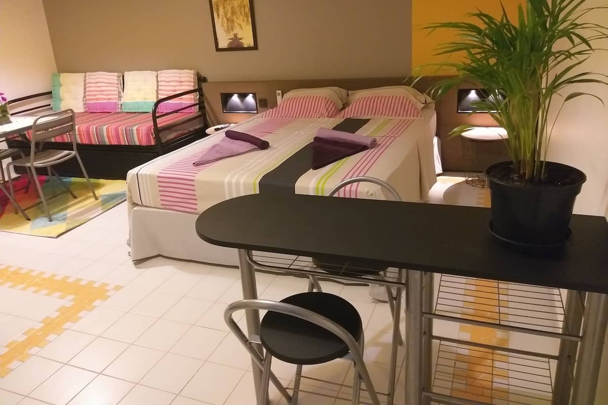 Une chambre d’hôtel avec un lit, un bureau, une chaise, une plante en pot et un téléviseur.