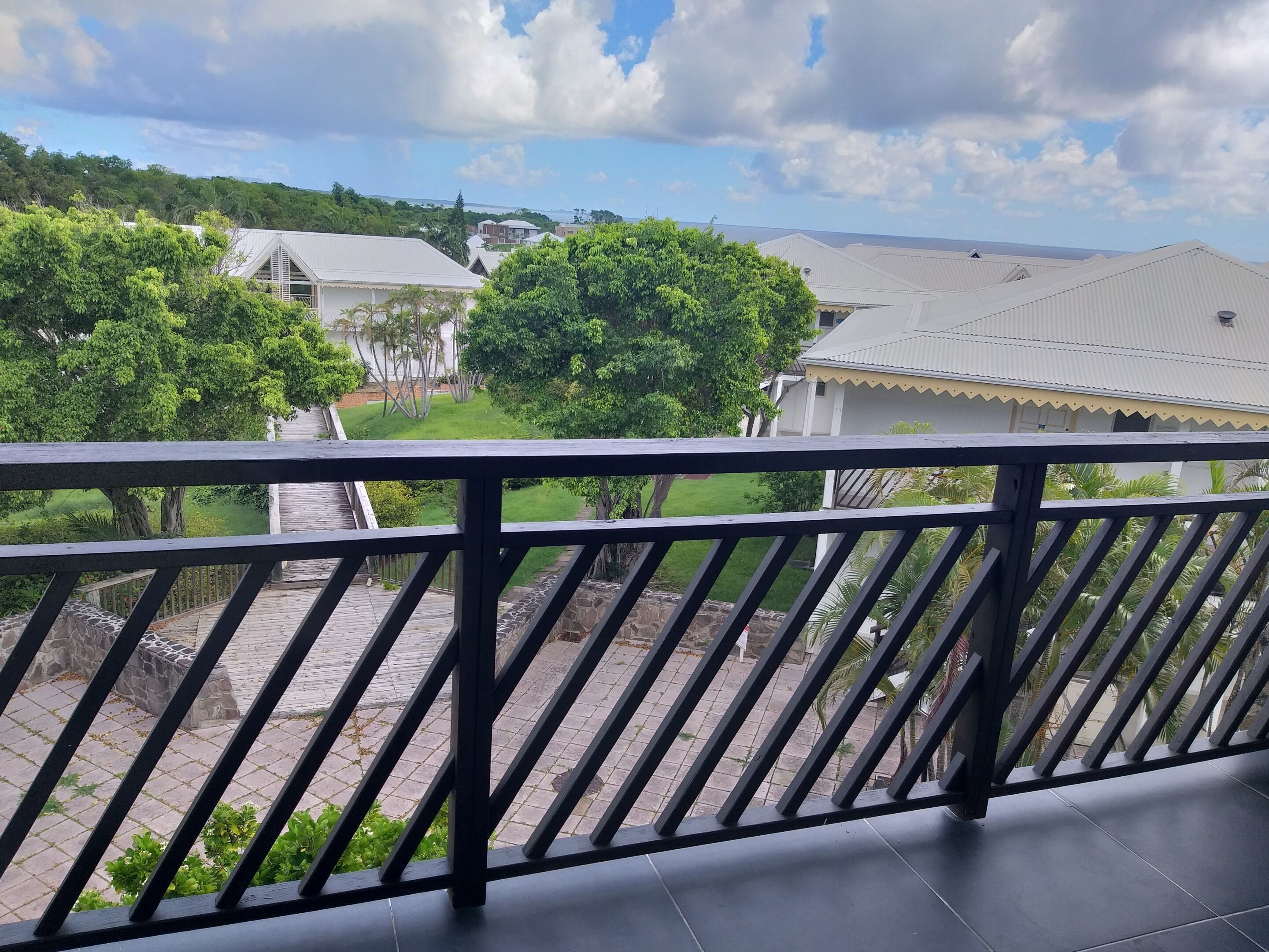 Een balkon met uitzicht over een woonwijk, met huizen en groen.