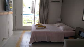 Habitación de hotel con cama, sofá, televisor, aire acondicionado y vistas al exterior.