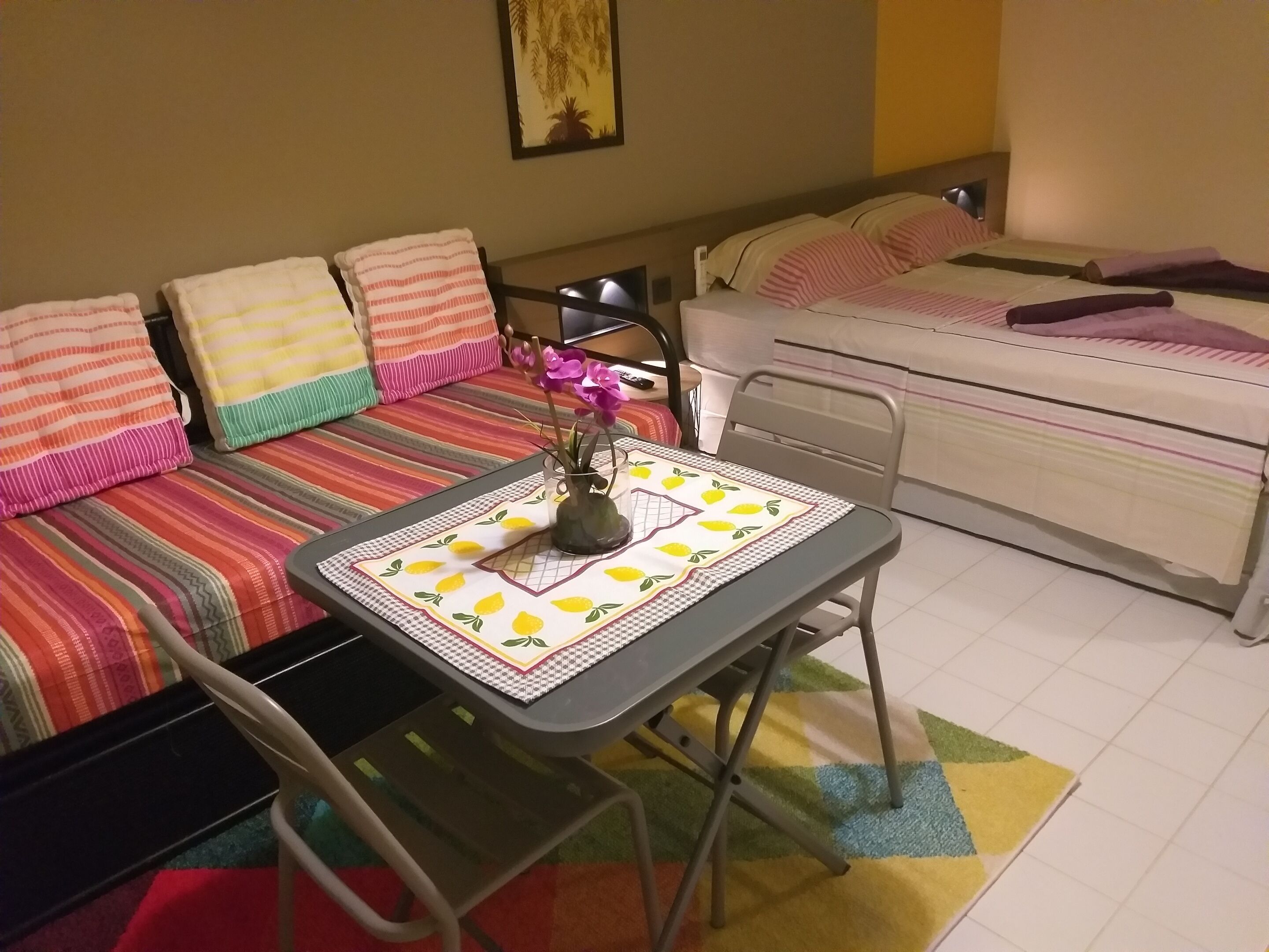 Una habitación pequeña y acogedora con cama, sofá, mesa con mantel y una silla.