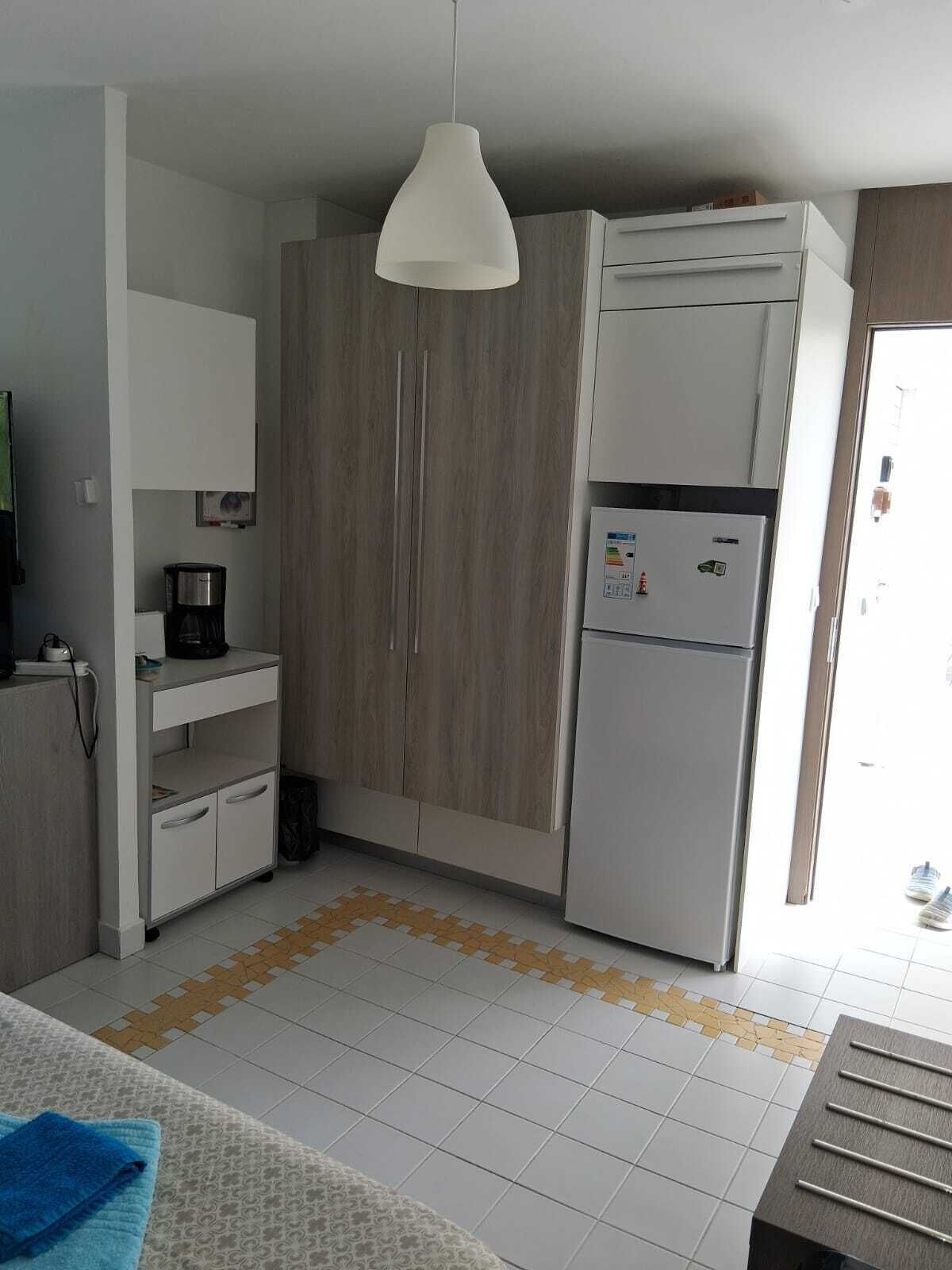 A compact kitchen with a refrigerator, a coffee maker, and a cabinet.