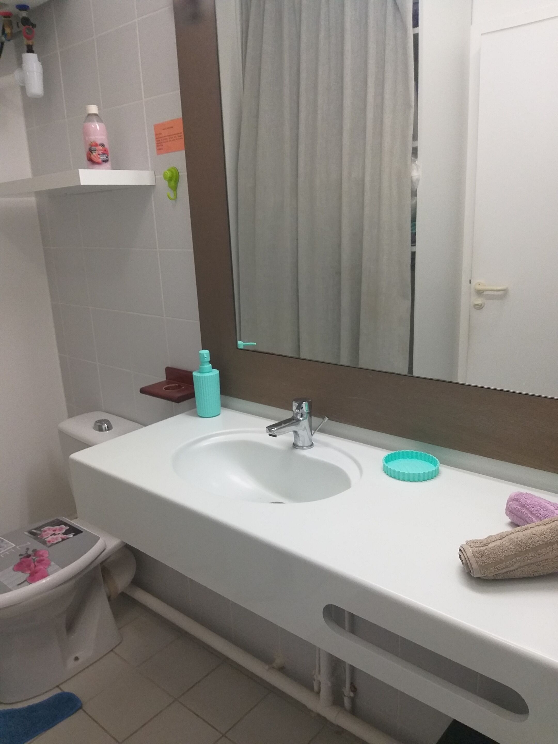 Ein Badezimmer mit Waschbecken, Spiegel, Handtuch und Toilette.