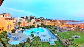 A hotel with a large swimming pool, multiple lounge areas, and a view of the sea. - Large terrace, 50m from beach with sea view + private pool (Six-Fours-les-Plages)