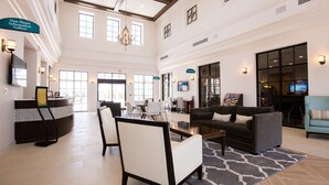 A spacious lobby with a reception desk, seating area, and a large chandelier. - Perfect Retreat 8BR/6BA Pool Home in Windsor at Westside! (Kissimmee)