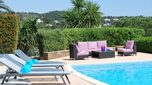 A poolside area with lounge chairs, a sofa, and a small table. - Splendid Sea View Villa near St-Tropez - Pool, AC, Sleeps 10 (Cavalaire-sur-Mer)