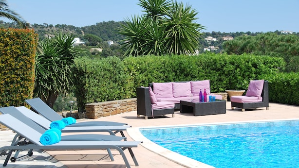 Un área junto a la piscina con sillones de descanso, un sofá y una mesita.