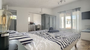 Un dormitorio con cama, escritorio, silla, armario y televisor.