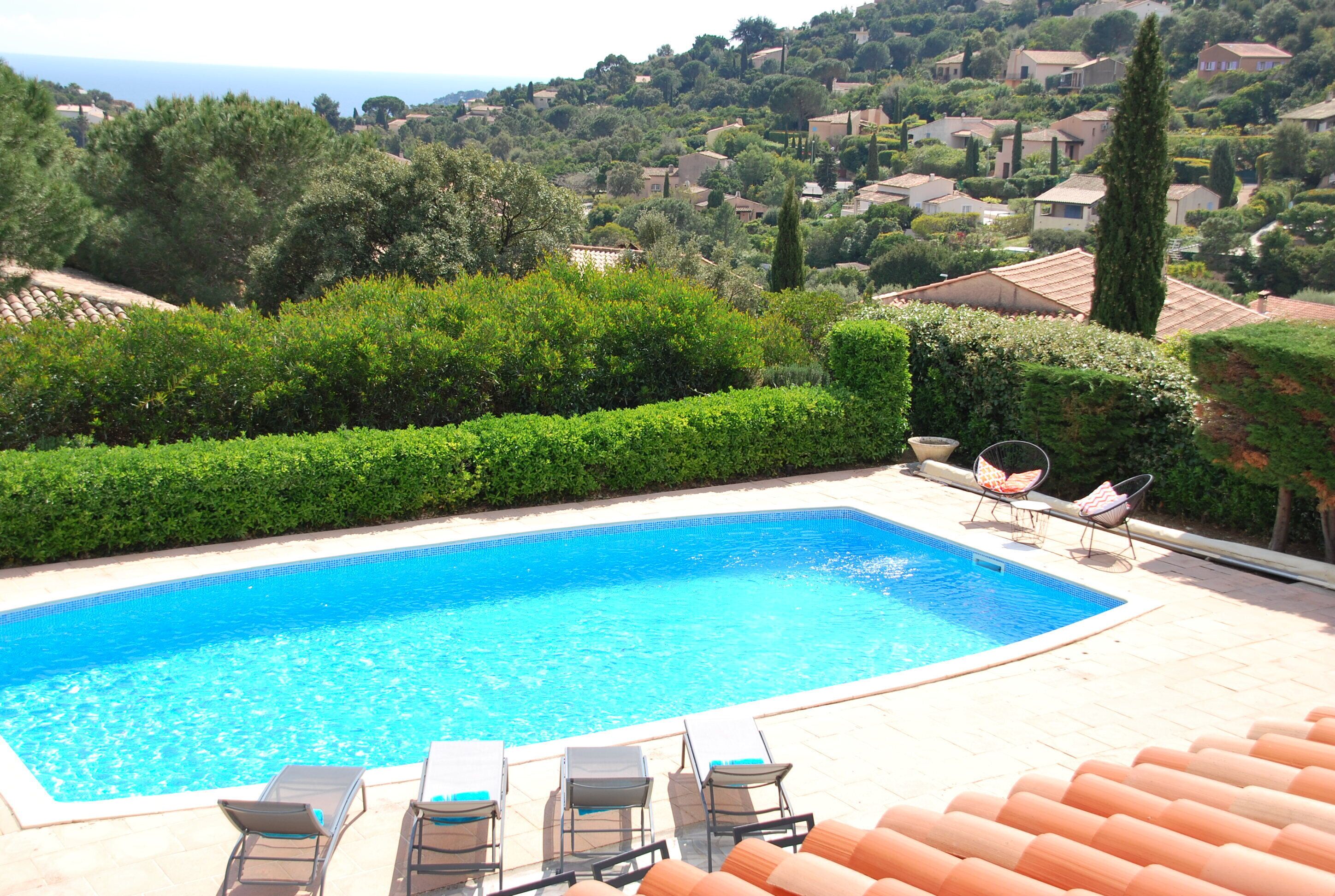 A swimming pool with lounge chairs and a view of a hillside residential area.