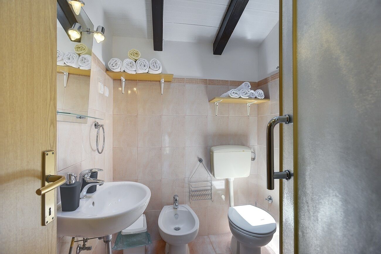 A modern bathroom with a sink, bidet, toilet, and towel storage.