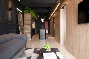 Eine moderne Lobby mit einer Couch, einem Couchtisch mit Pflanze und einem Empfangstresen.