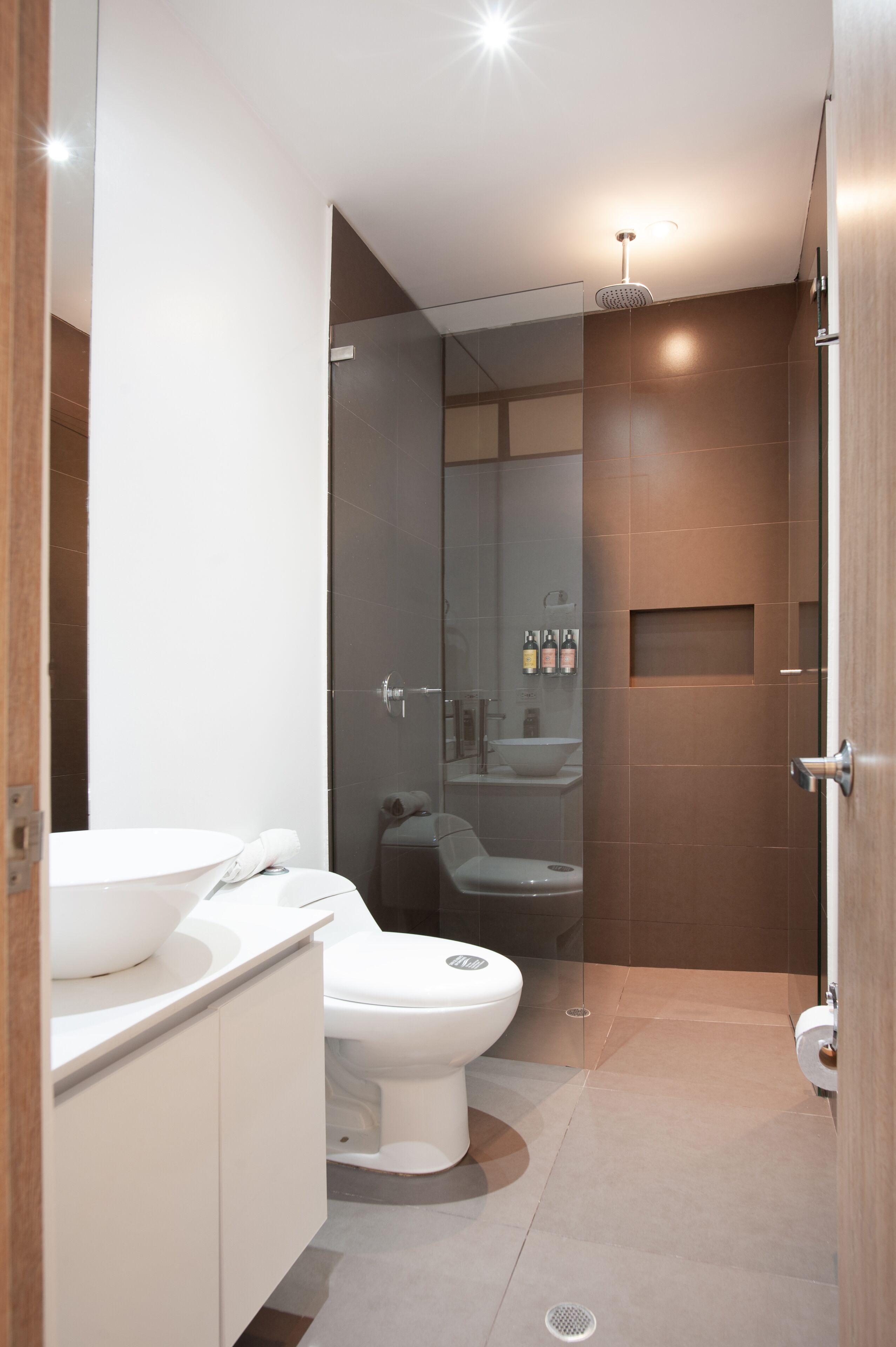 A modern bathroom with a toilet, bidet, and a glass-enclosed shower area.