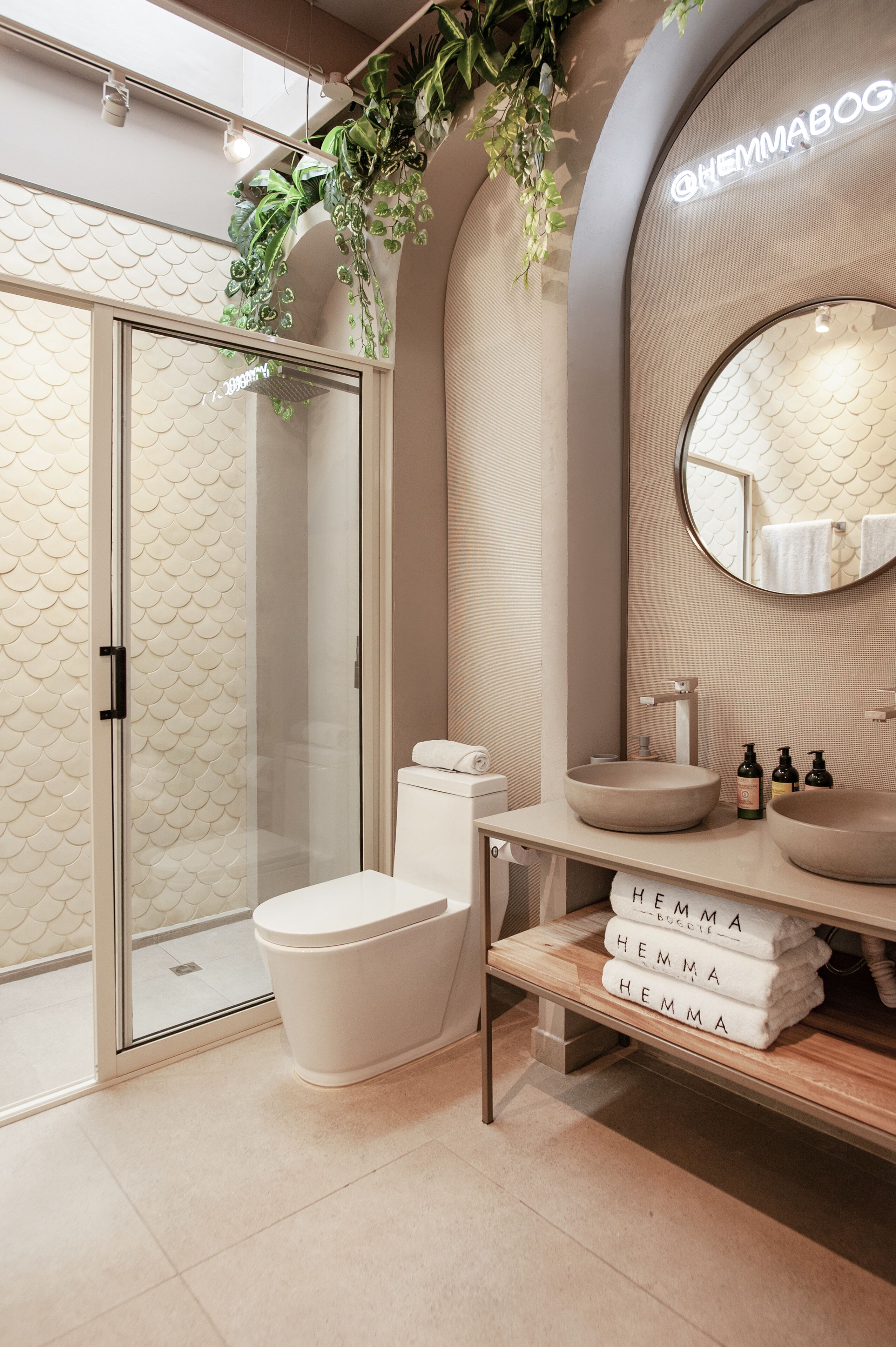 A modern bathroom with a glass-enclosed shower, a round mirror, and a beige sink.