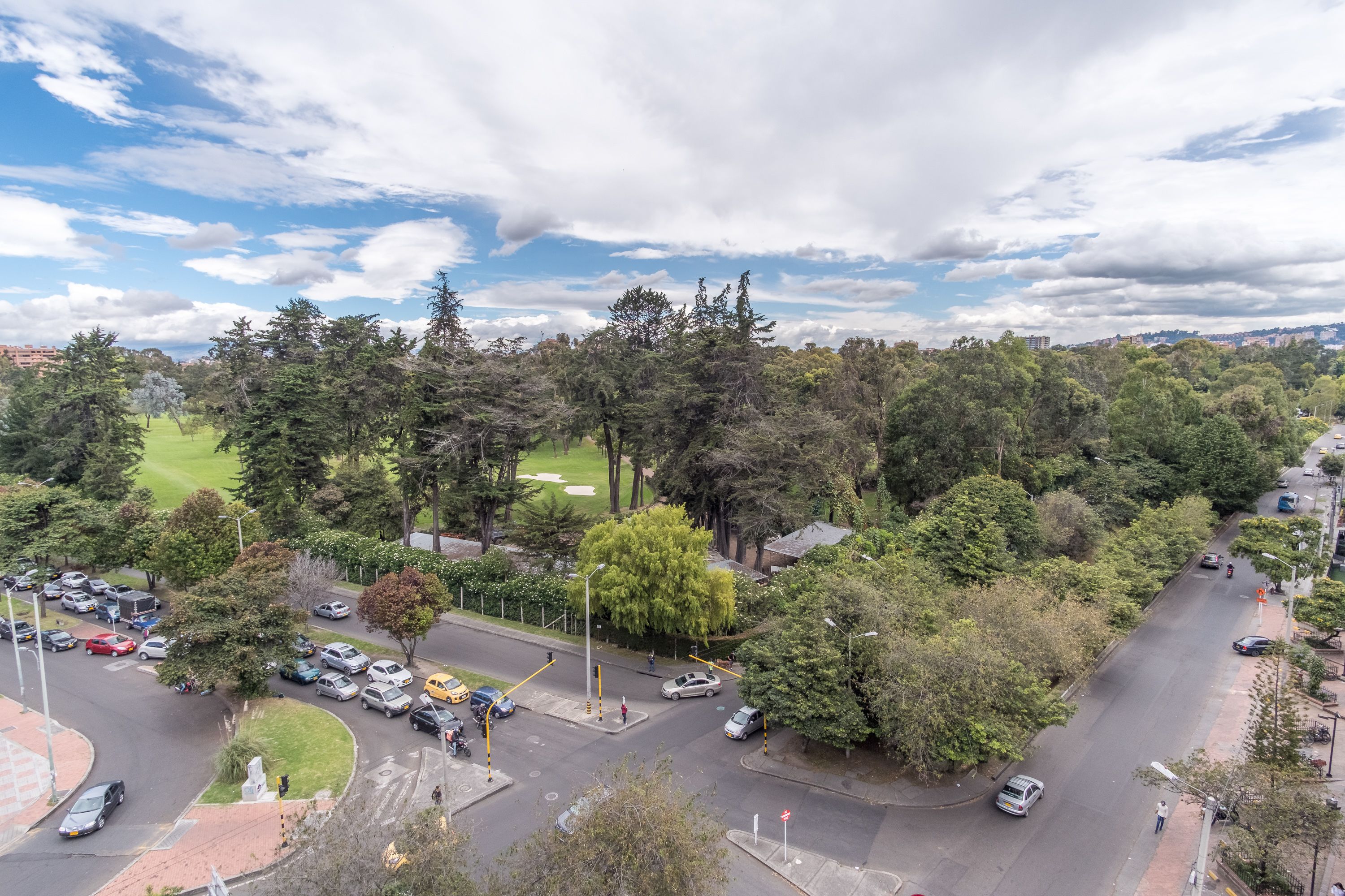 An aerial view of a city intersection surrounded by dense trees and a golf course.