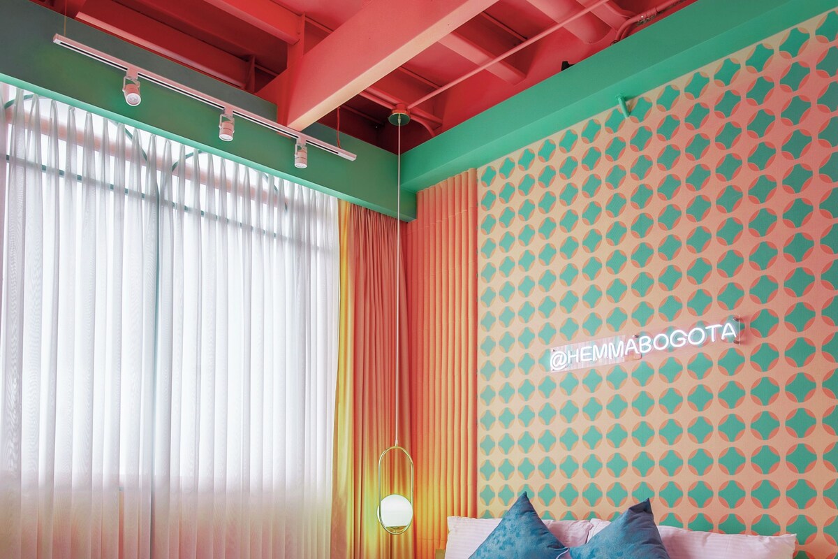 A bedroom with a bed, curtains, and a patterned wall.