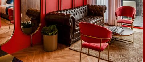 Un salon moderne avec un mur d’accent rouge, un canapé en cuir, un fauteuil rouge et un grand miroir.
