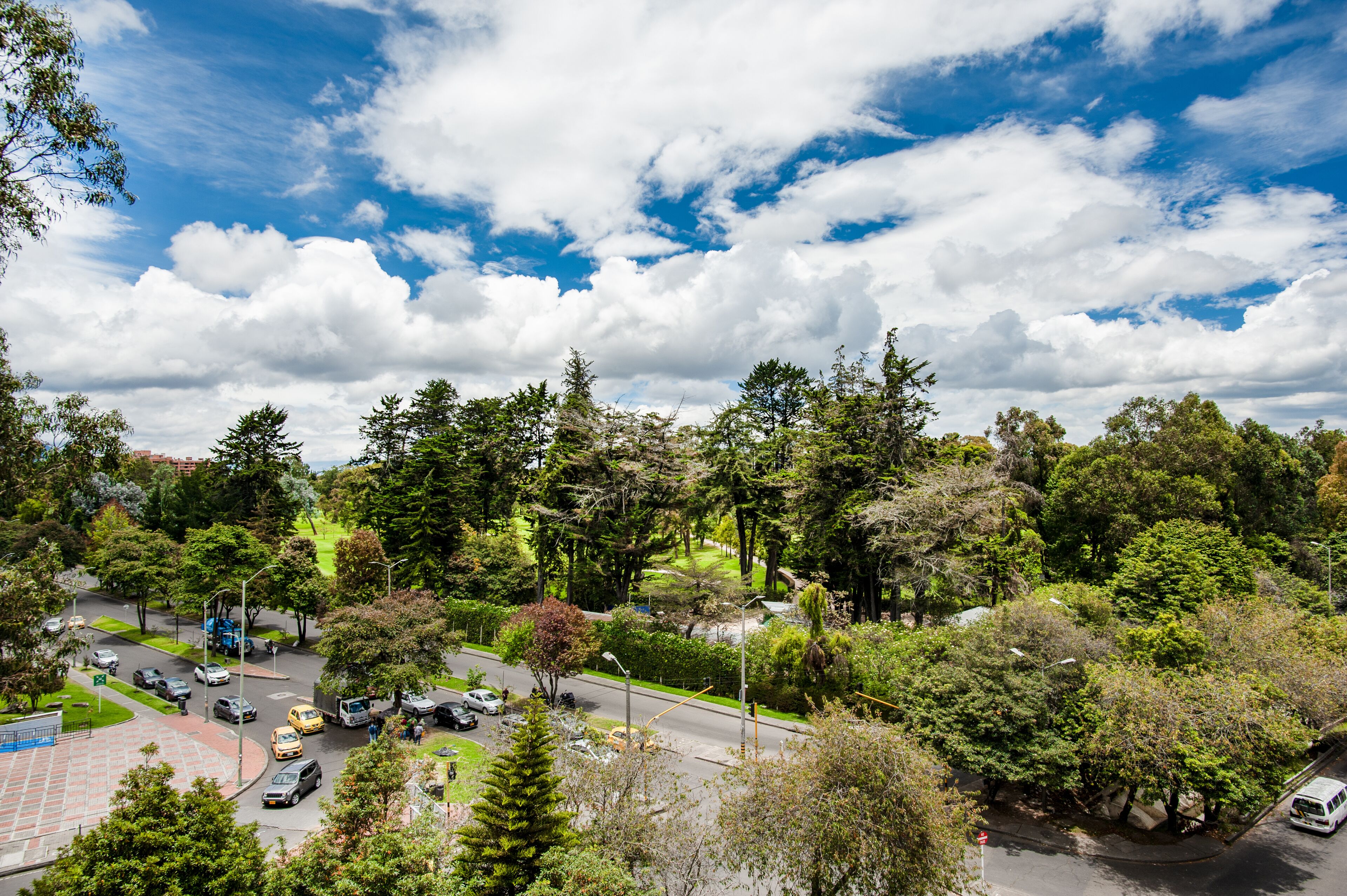 A multi-story building with a central courtyard, surrounded by lush greenery and trees.
