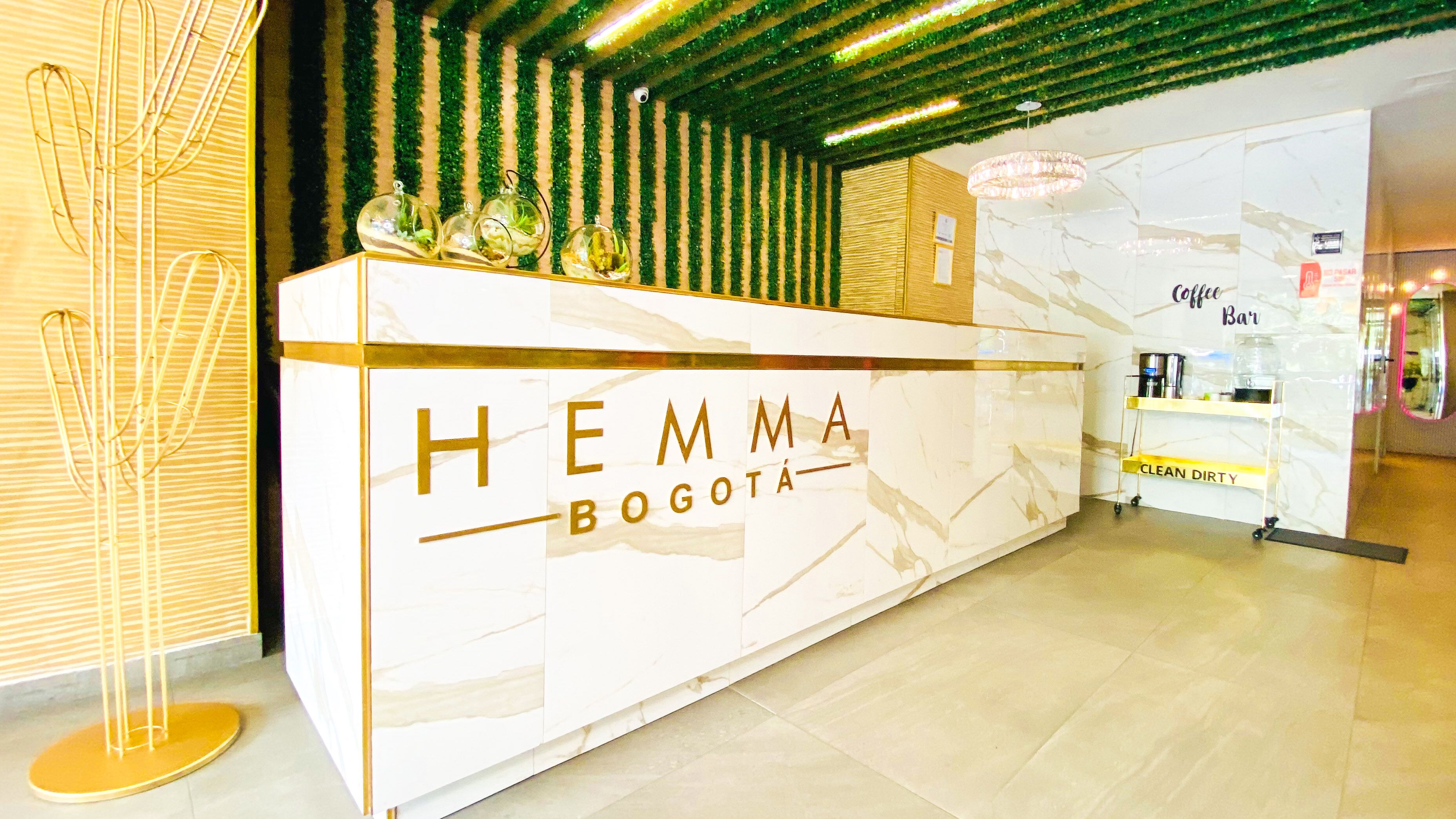 Een receptiebalie met de aanduiding 'HEMMA BOGOTA', een schoon, marmerachtig oppervlak en een bord met 'CLEAN DIRTY' erop.