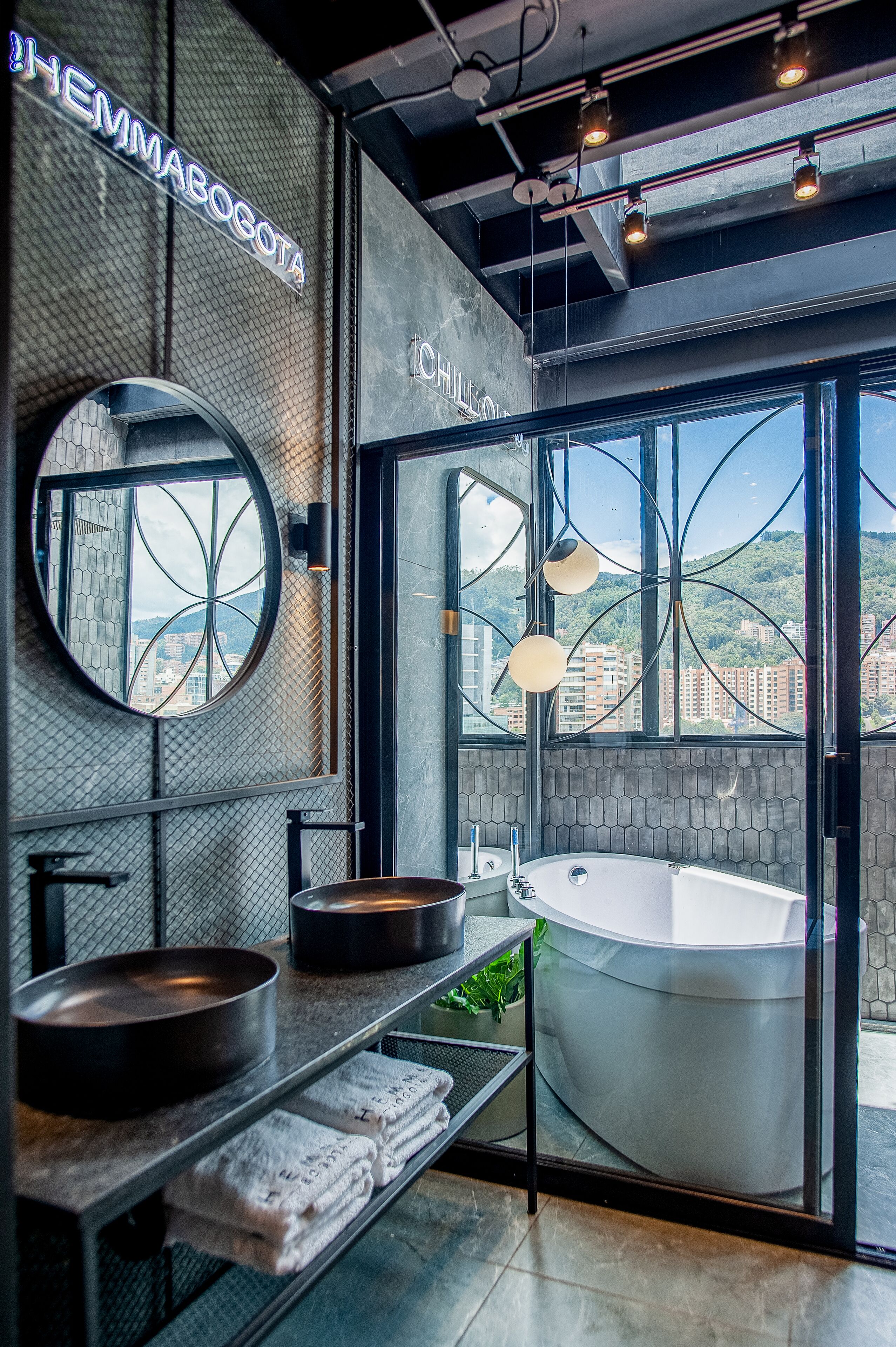 Un baño moderno con una bañera grande, un espejo redondo y un lavabo doble.