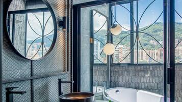 Un baño moderno con una bañera grande, un espejo redondo y un lavabo doble.