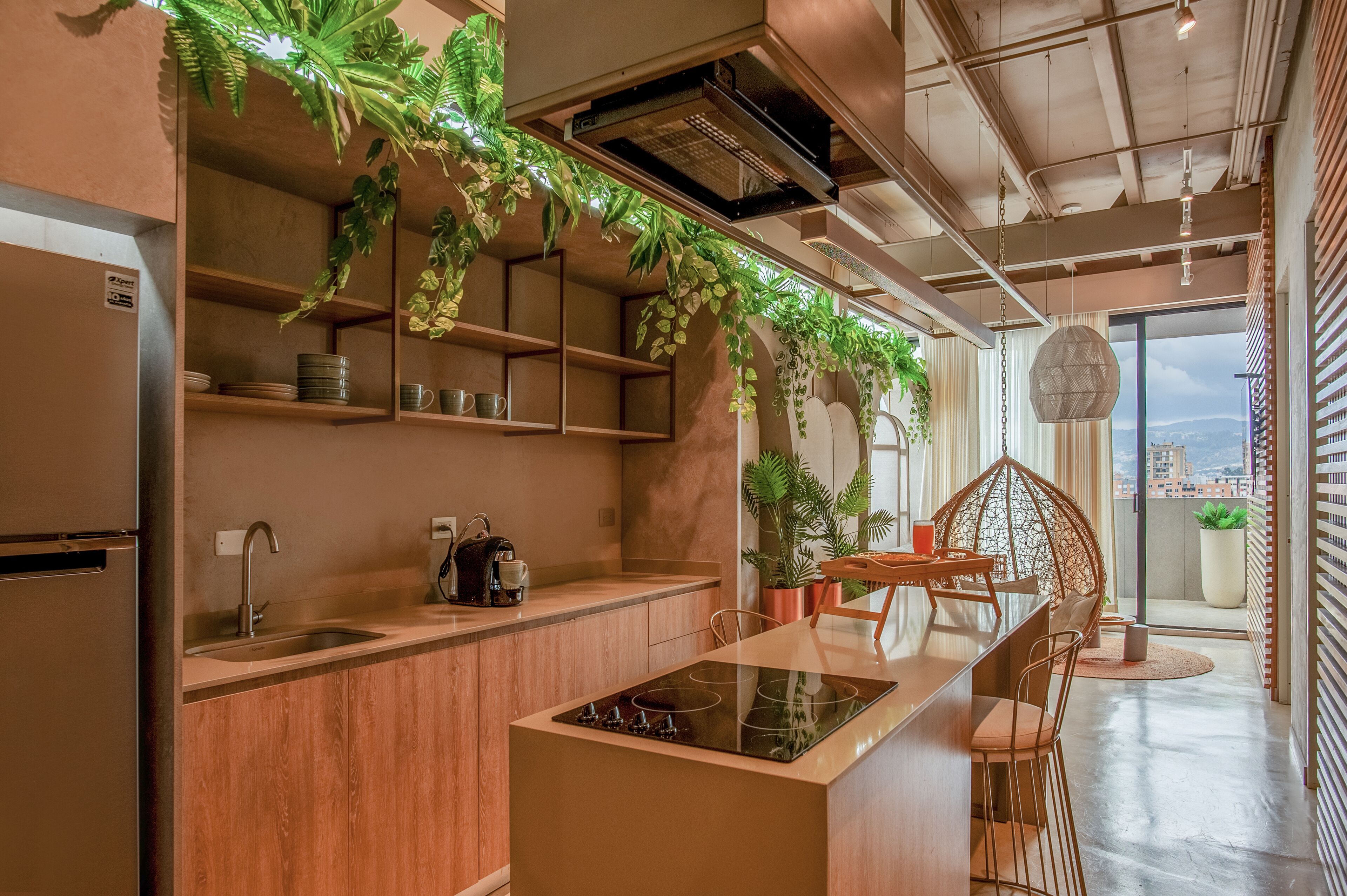 Una cocina moderna con armarios de madera, estufa integrada y plantas colgantes.