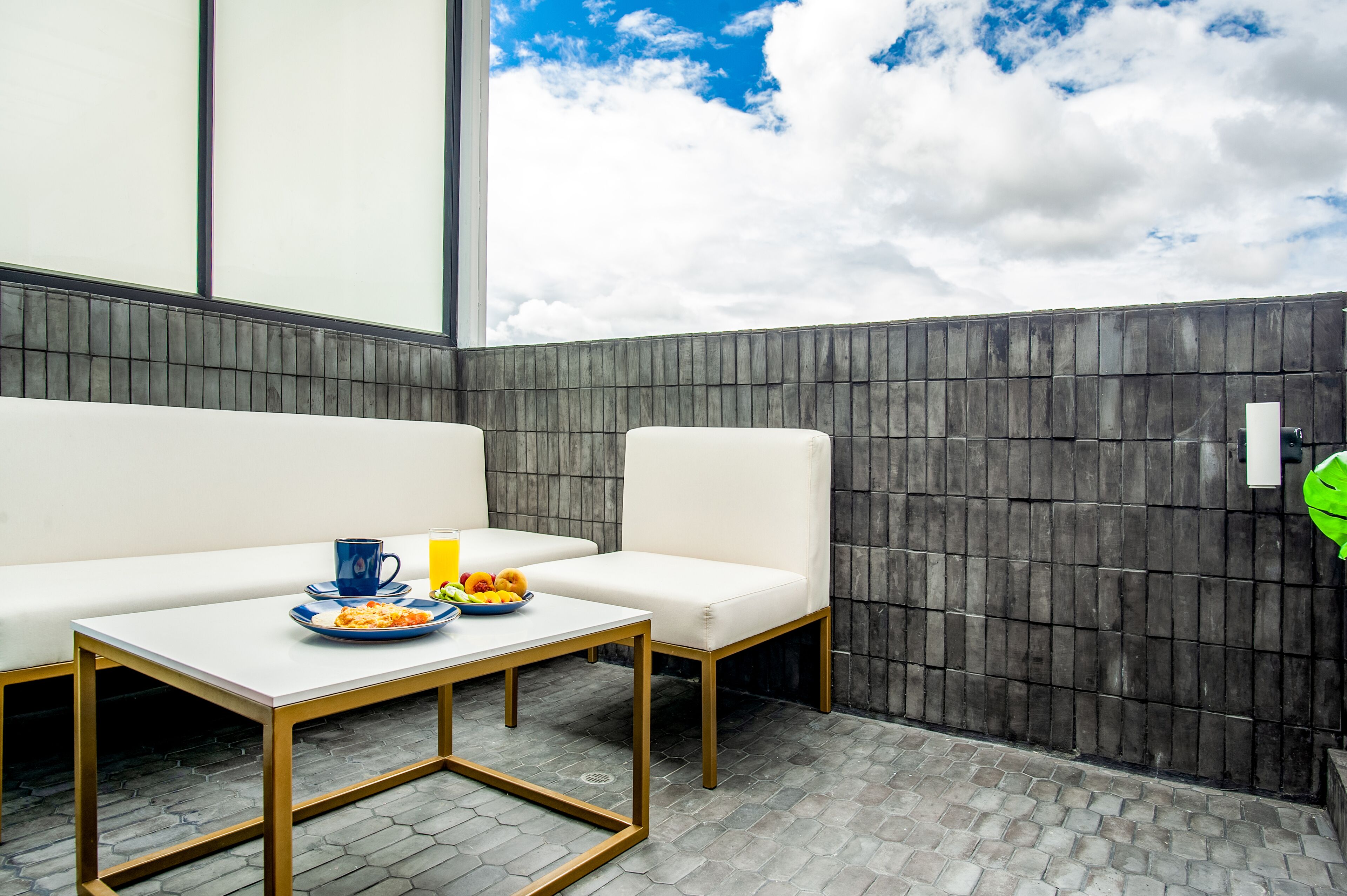 A modern outdoor seating area with a white table and chairs, a blue cup, and a fruit bowl.