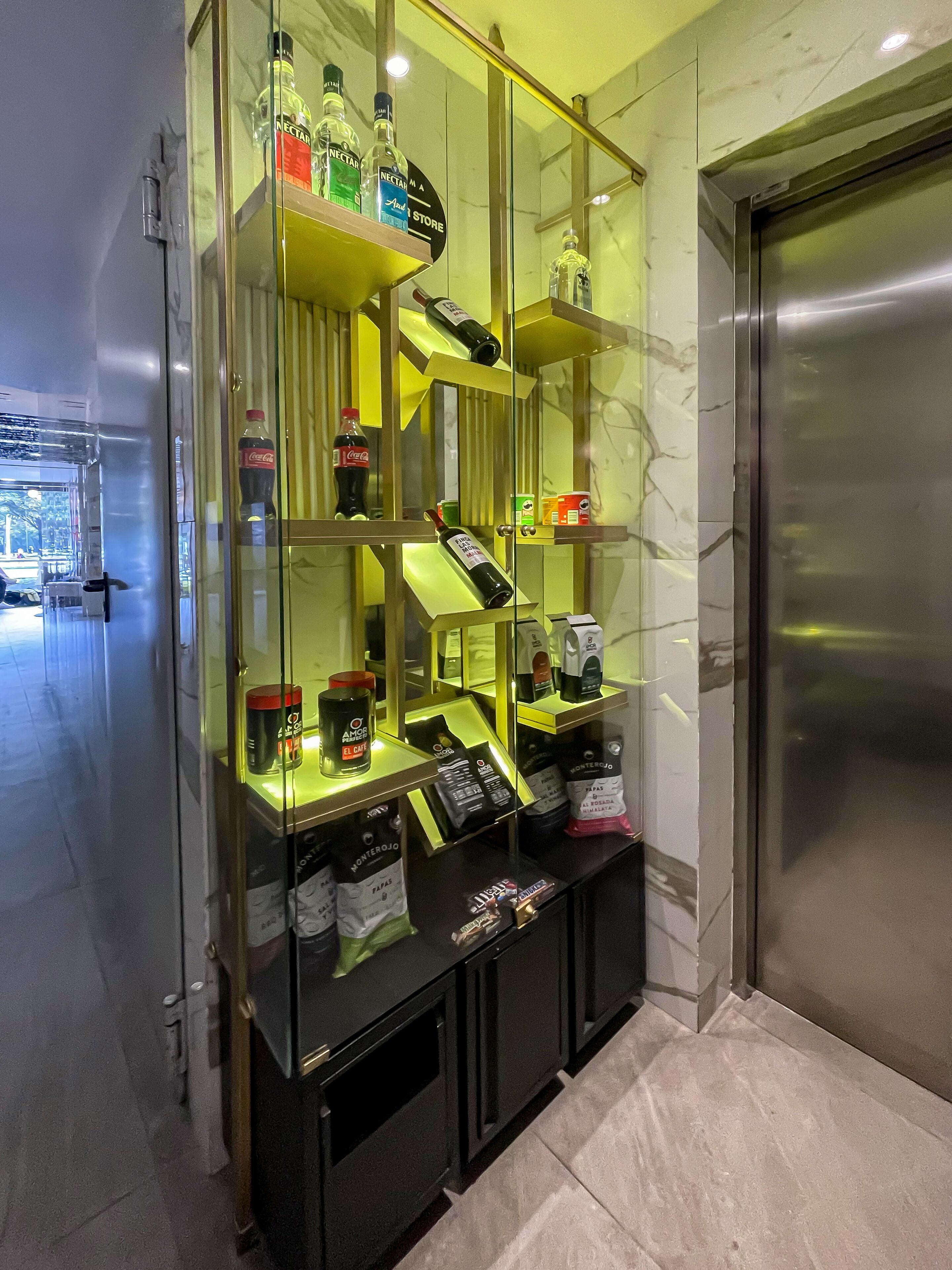 A glass display case with various bottles and packaged goods, including beverages and snacks, in a hotel lobby.