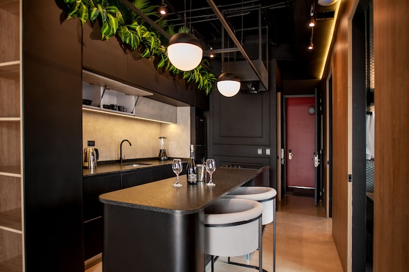 Una cocina moderna con una isla central, taburetes de bar e iluminación colgante.