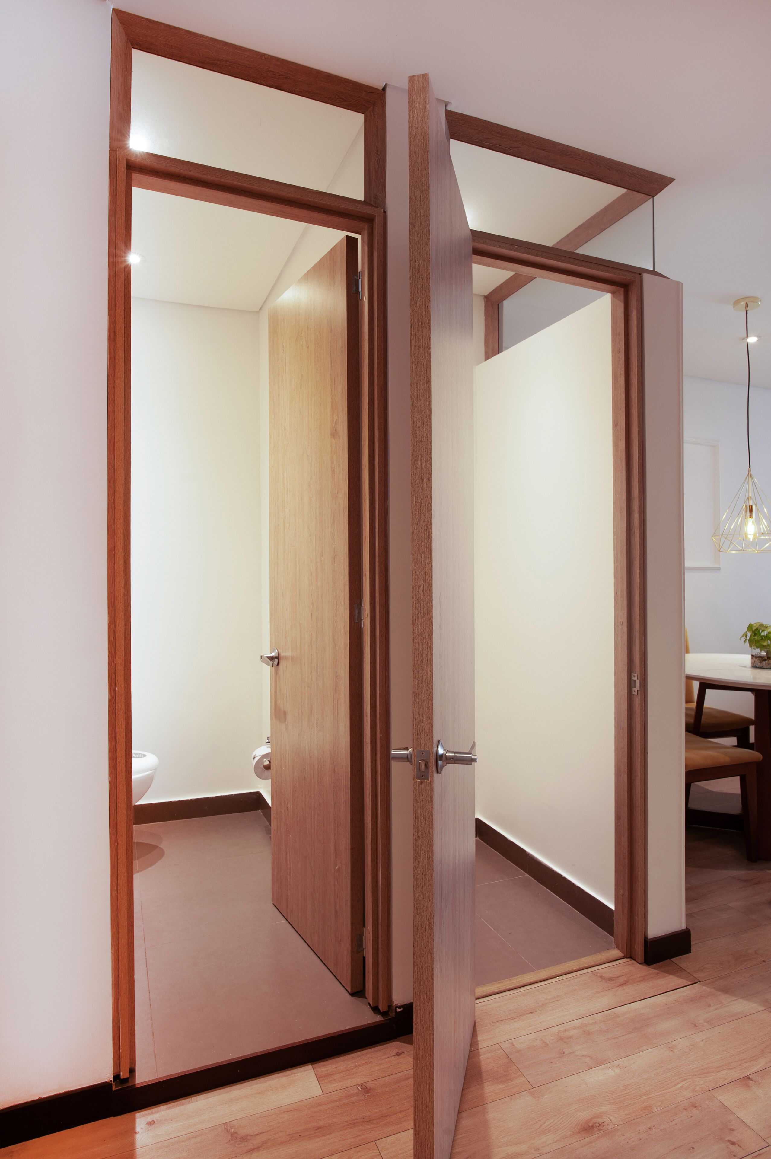 A room with a wooden door leading to a bathroom and a dining area.