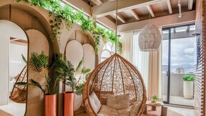 Un interior moderno con una silla colgante, plantas grandes en macetas y vistas de la ciudad.