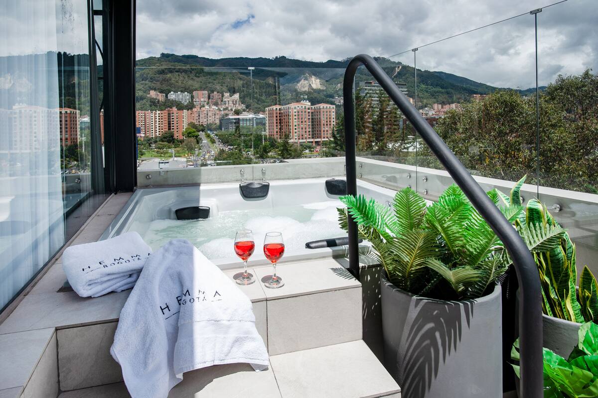 A balcony with a hot tub, two glasses of red wine, and a towel with text.