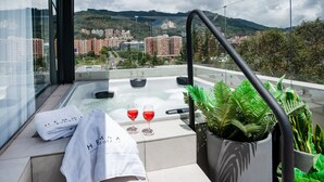 Un balcón con jacuzzi, dos copas de vino tinto y una toalla con texto.