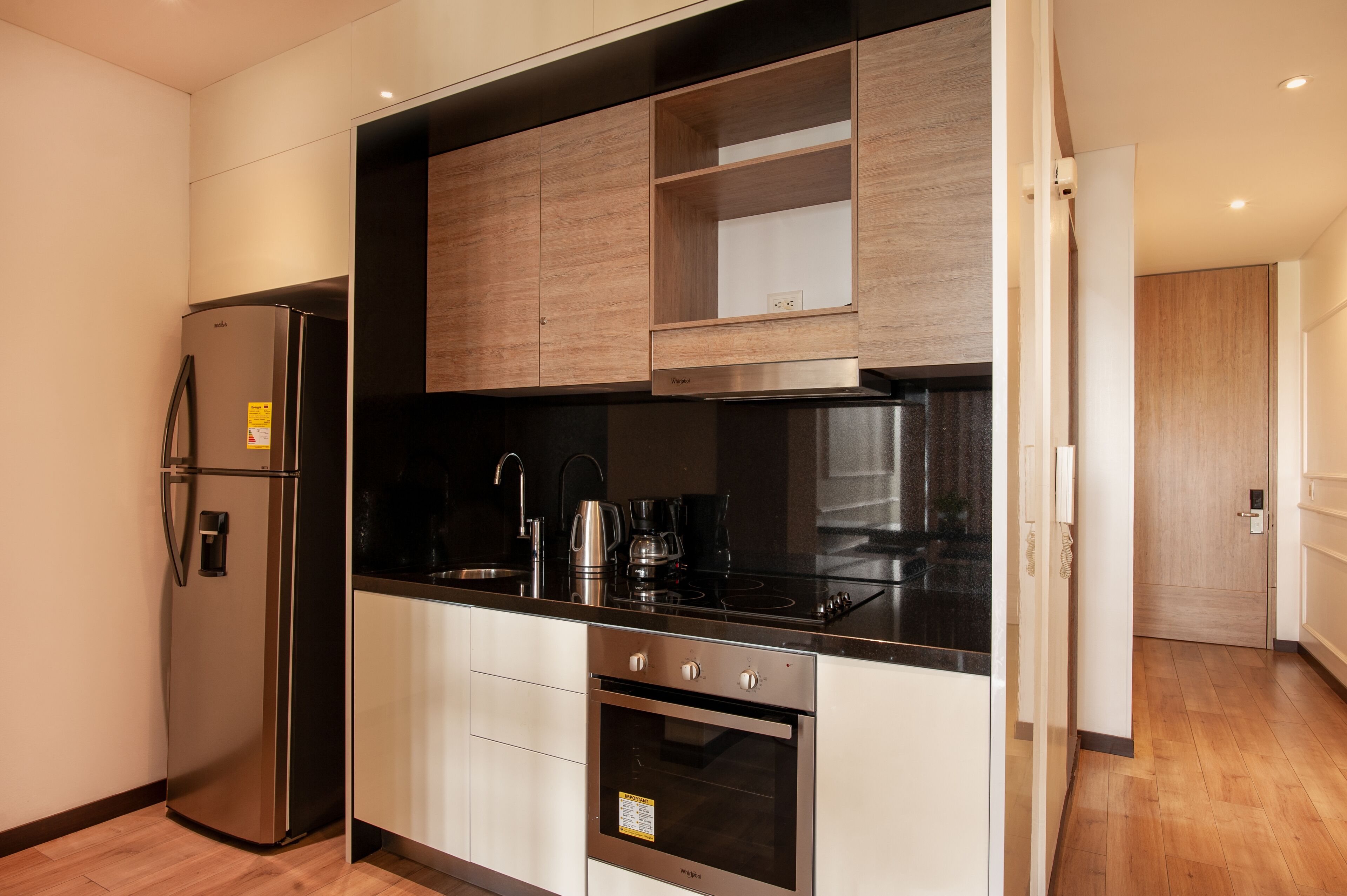 A modern kitchen with a stainless steel refrigerator, a built-in oven, and a black countertop.