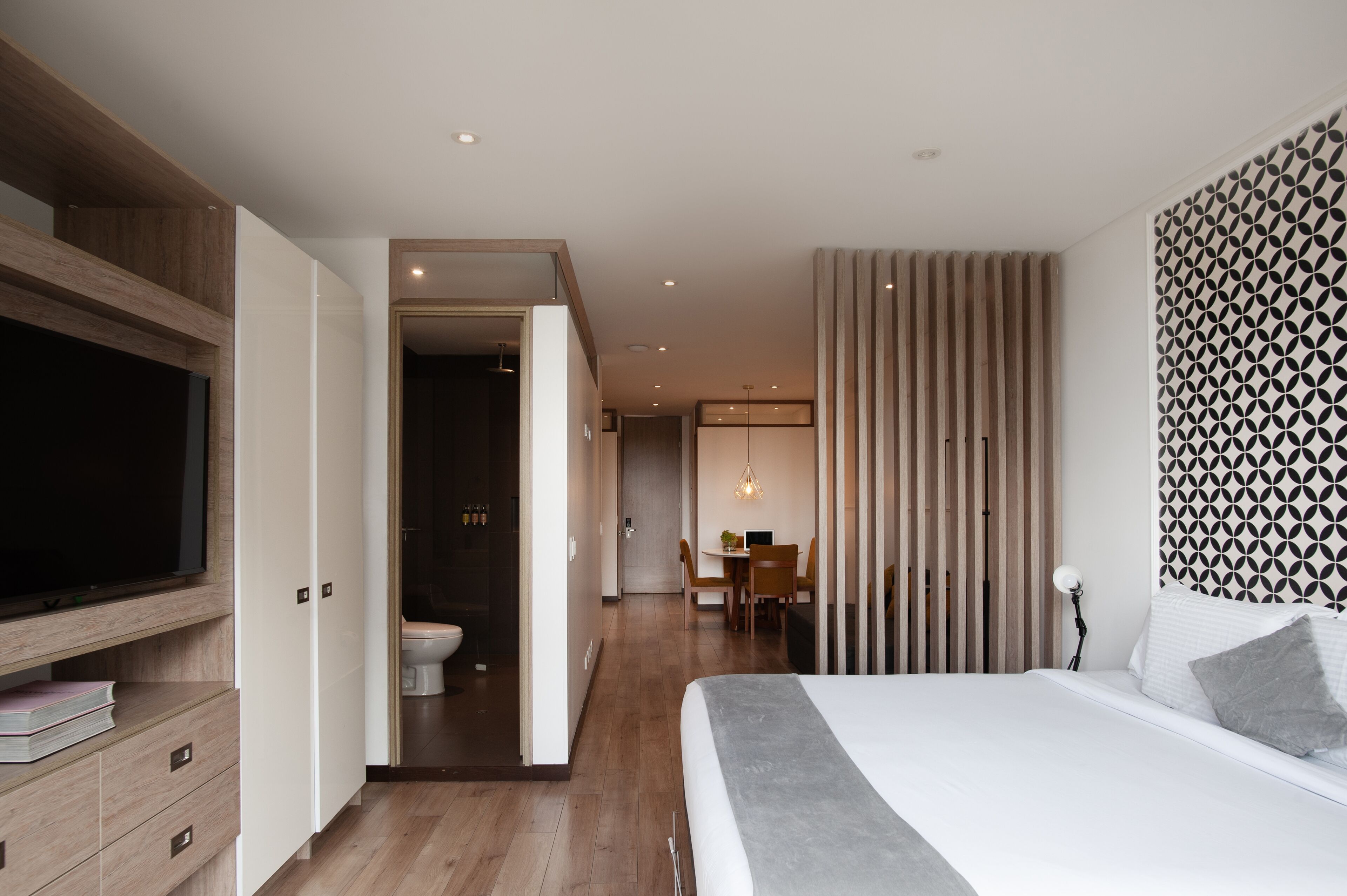 A modern hotel room with a large bed, a TV, a desk, and a bathroom.