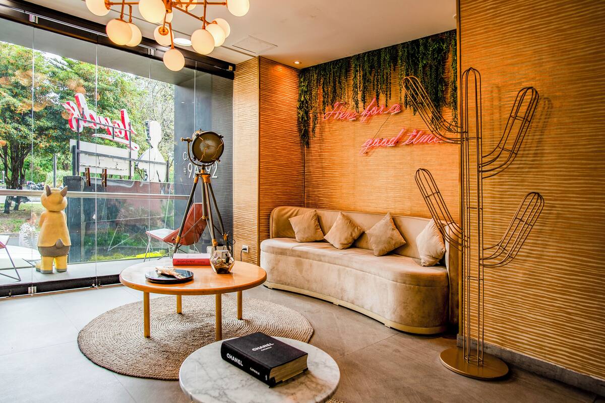Un interior moderno con un sofá, una mesa redonda, un cactus decorativo y vistas al exterior.