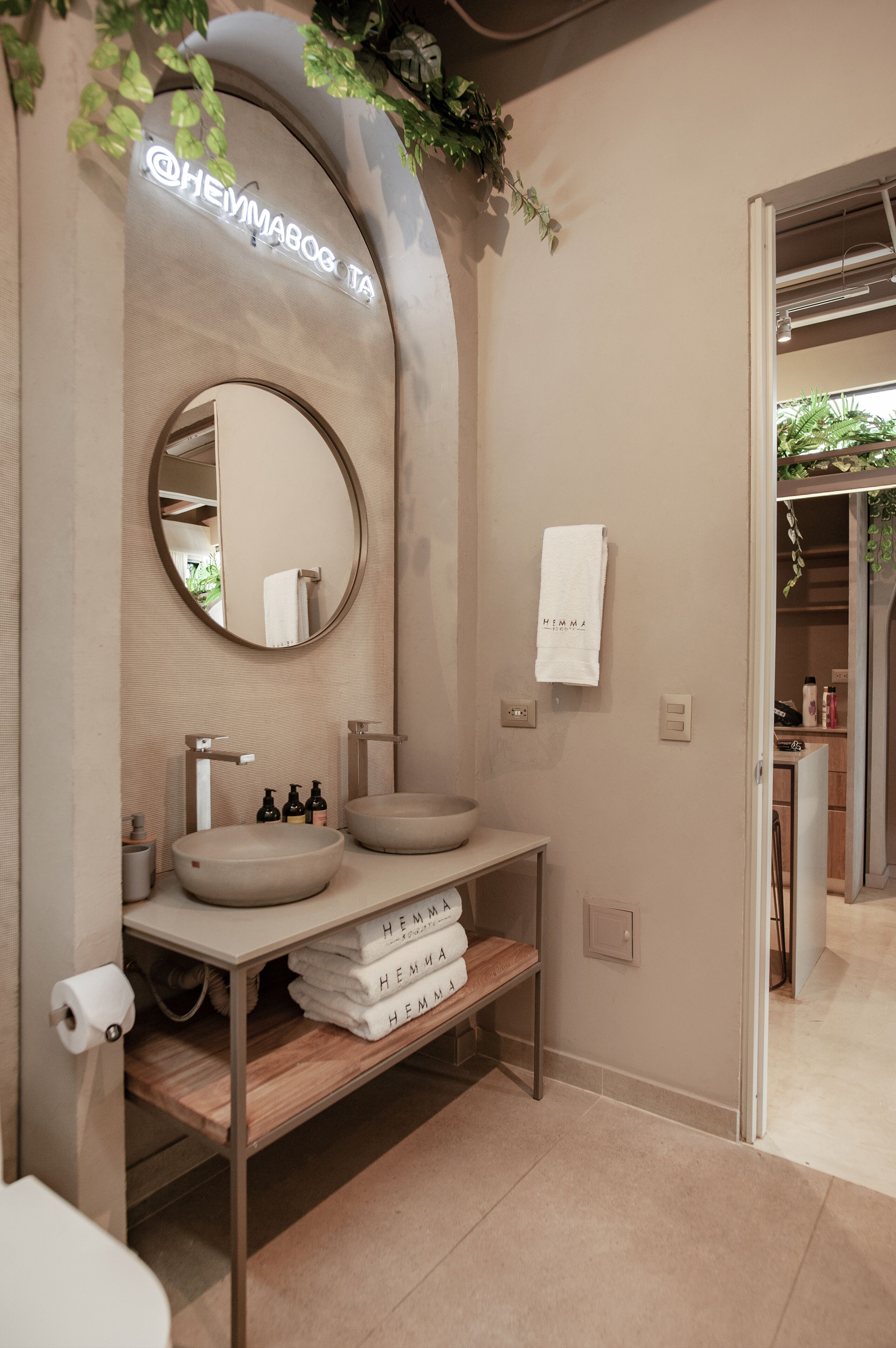 A modern bathroom with a round mirror, two sinks, and a towel rack.
