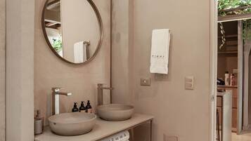 A modern bathroom with a round mirror, two sinks, and a towel rack.