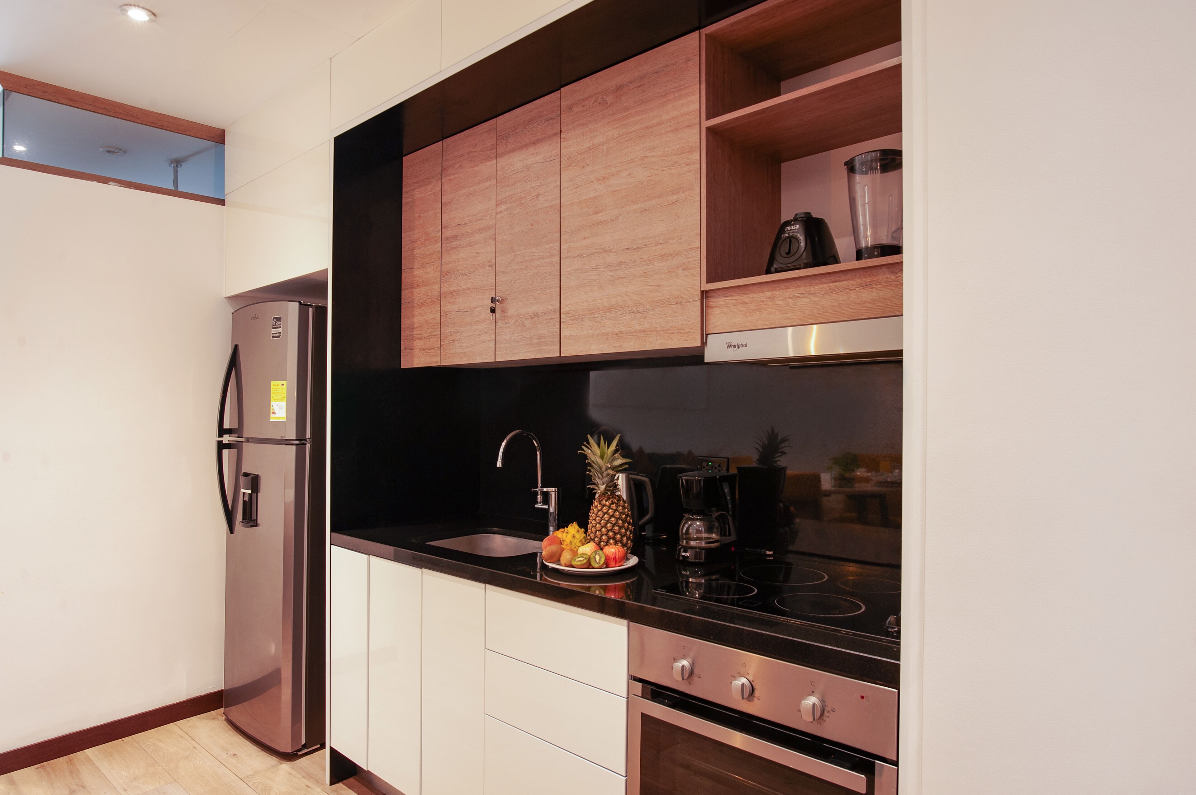 Una cocina moderna con electrodomésticos de acero inoxidable, armarios de madera y encimera negra.