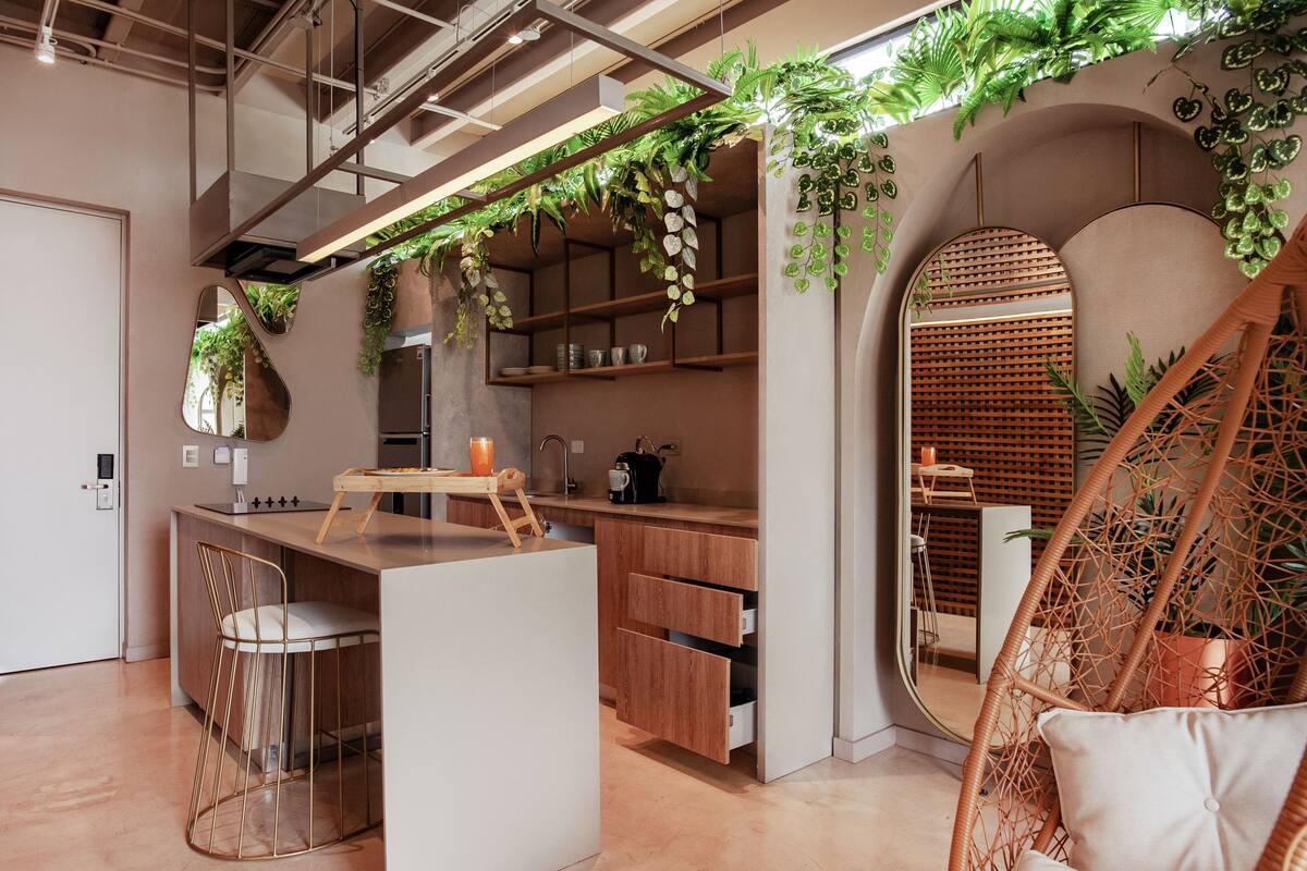 A modern kitchen with wooden cabinets, a central island, and hanging plants.