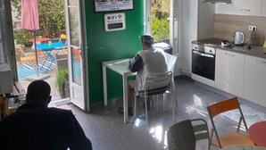 Un interior moderno con una pared de acento verde, una zona de cocina y un área de descanso con una mesa y sillas.