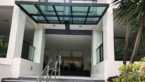A building entrance with a glass canopy, a staircase, and a small garden area with plants and flowers. - BEAUTIFUL APARTMENT IN RIVIERA DE SÃO LOURENÇO, MODULE 4 (Riviera de São Lourenço)