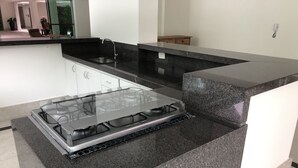 A modern kitchen with a gas stove, black countertops, and white cabinets. - BEAUTIFUL APARTMENT IN RIVIERA DE SÃO LOURENÇO, MODULE 4 (Riviera de São Lourenço)
