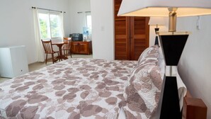 A bedroom with a bed, a desk, and a chair. - "Experience Tranquility at Hibiscus Studio" (Caye Caulker)