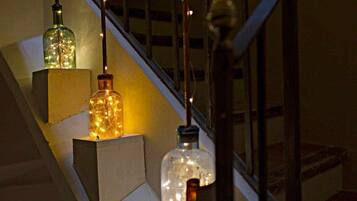 Tres botellas de vidrio con luces en su interior, colgadas de una escalera.