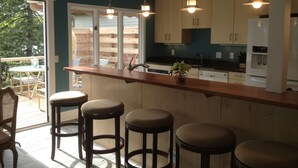 A kitchen with wooden cabinets, a bar area with stools, and pendant lighting. - Luxury Harbor Front Home In Town Chef's Kitchen 4 Ensuite King Rooms + 1/2 bath (Saugatuck)
