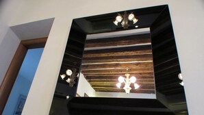 Espejo con detalles de panel de madera en la parte trasera, fijado a una pared blanca.