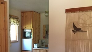 Ein kompakter Wohnraum mit Küchenzeile, Essbereich und einem grünen Sofa.