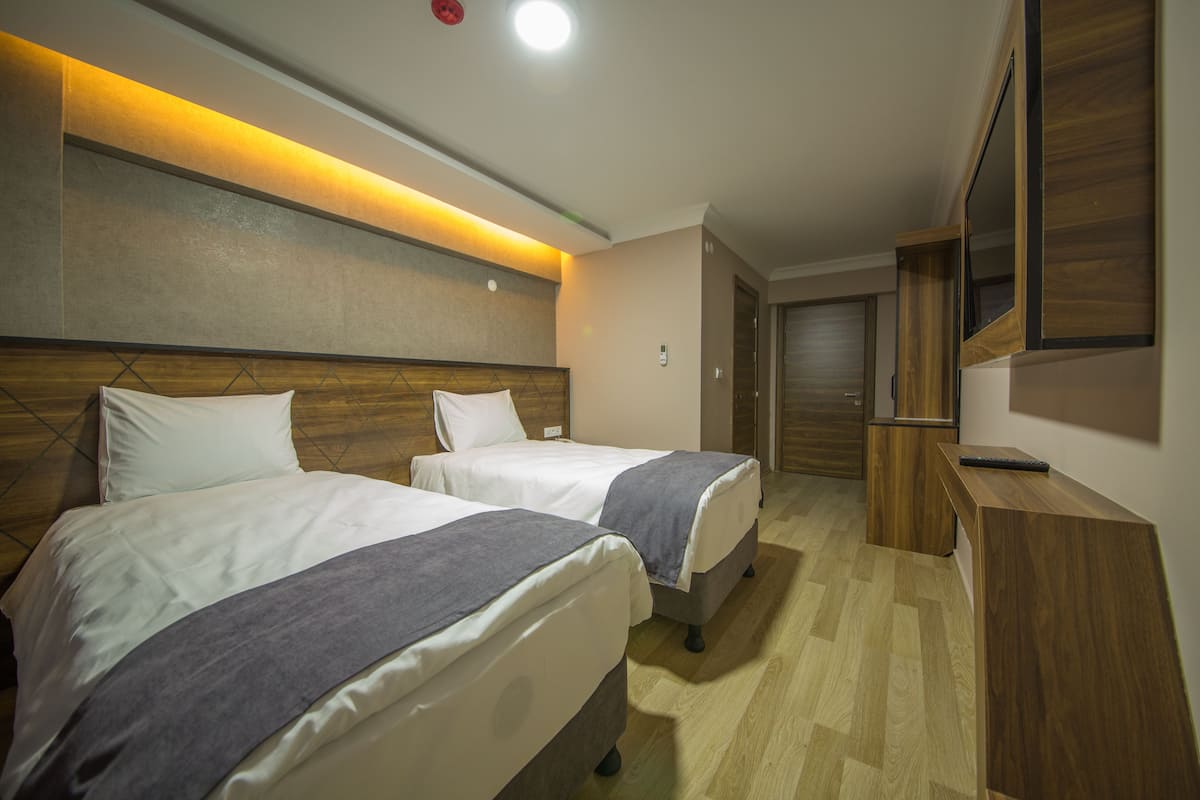 Habitación de hotel con dos camas, cabeceros de madera, un escritorio de madera y un espejo grande.