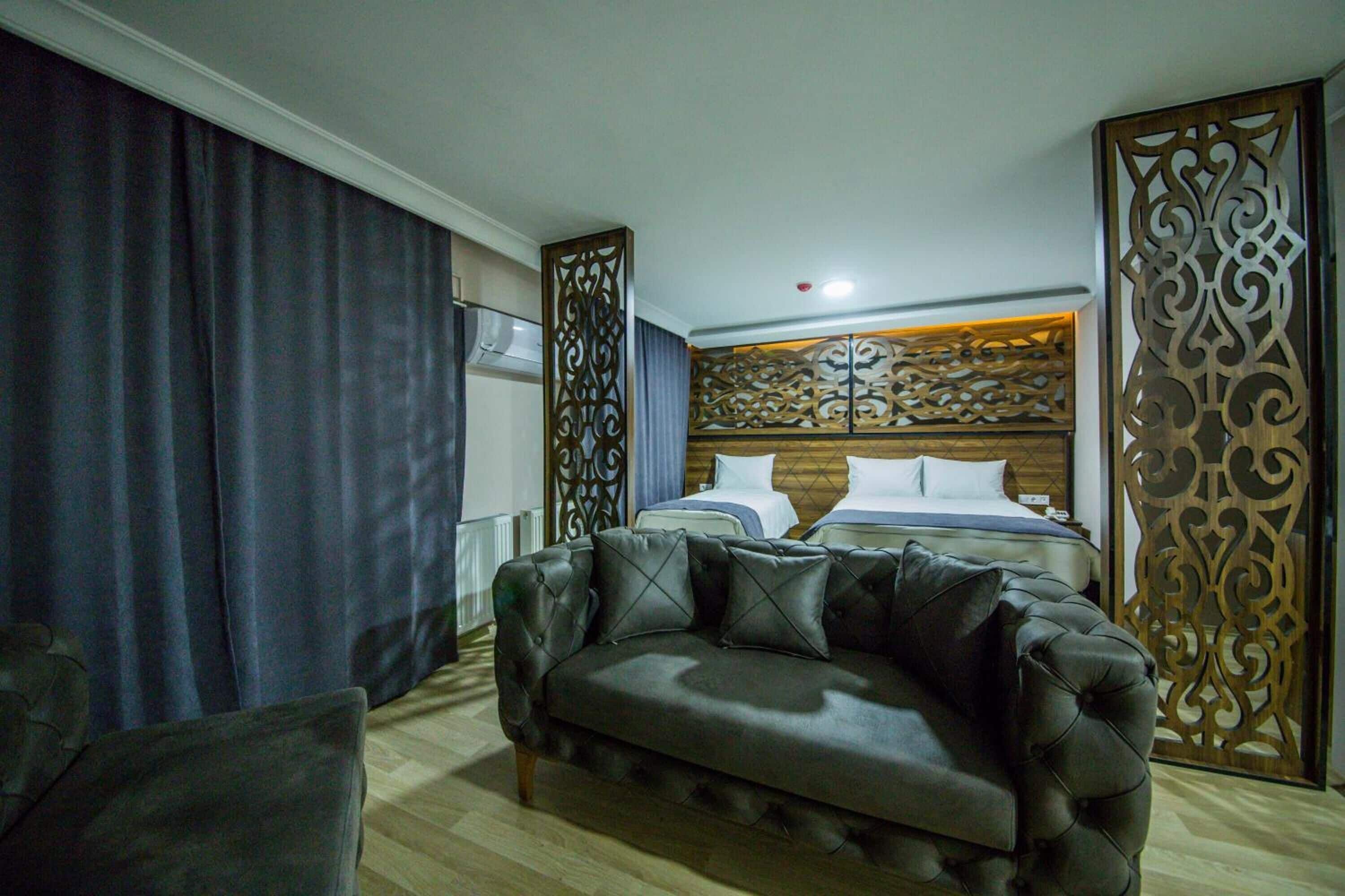 A hotel room with a large bed, a sofa, and a decorative headboard.
