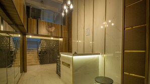 Et receptionsområde med marmorgulv, en receptionsdisk og en trappe op til en etage.