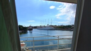 Une vue depuis un balcon, avec un ciel dégagé, un grand navire et une étendue d’eau calme.